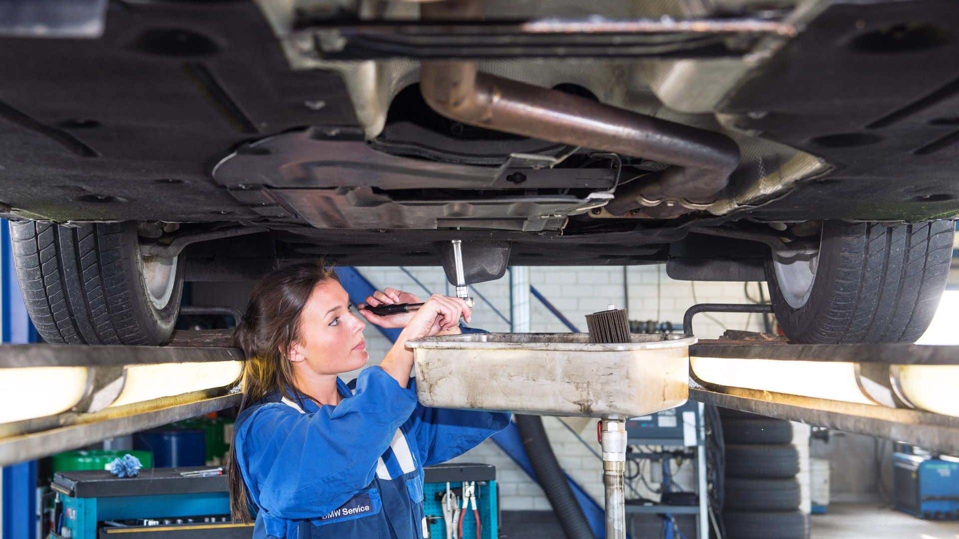 一位女机械师给汽车换油。