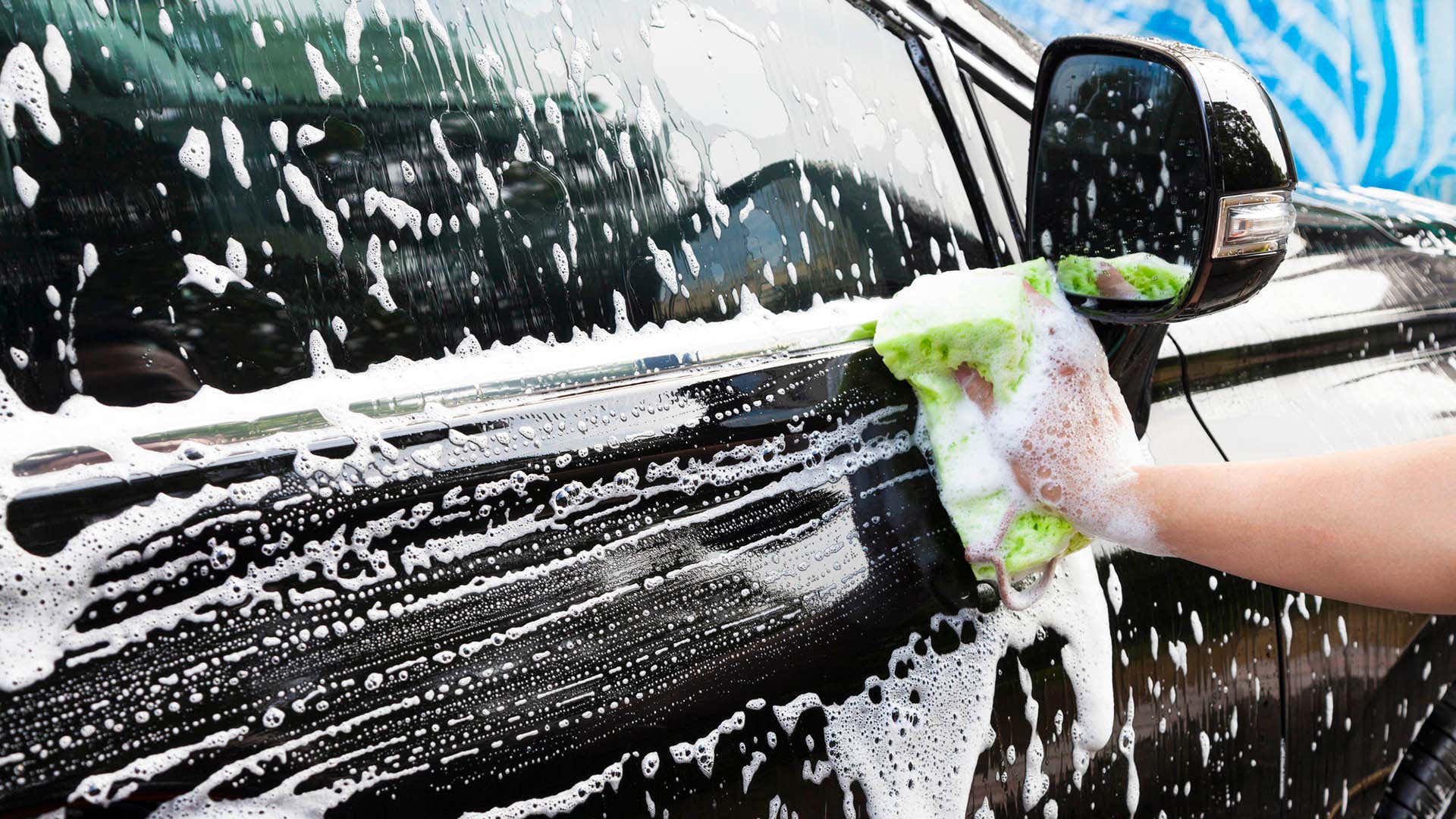 用海绵擦肥皂的车门的手。