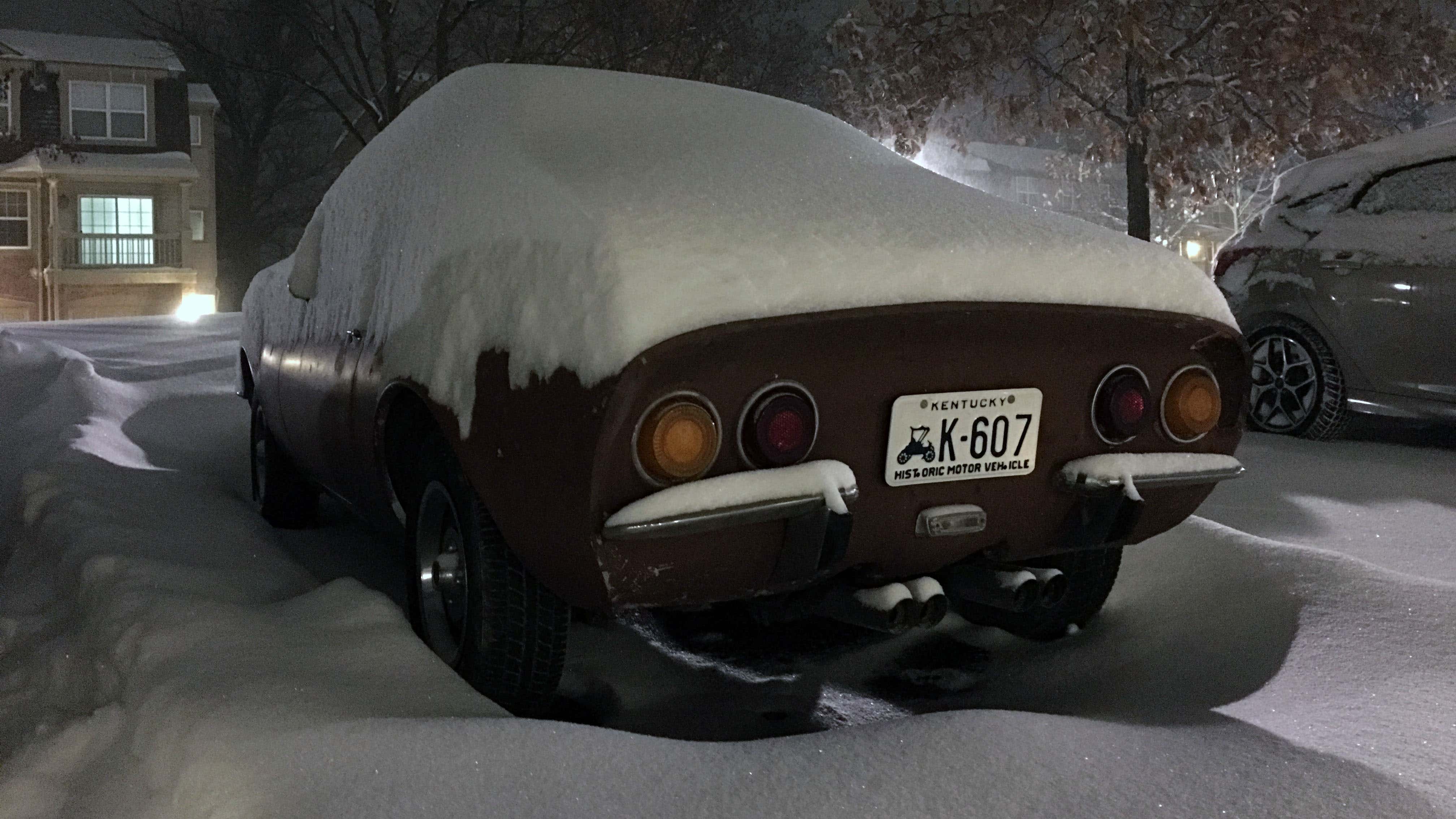 一辆欧宝GT停在被雪埋着的停车场里。